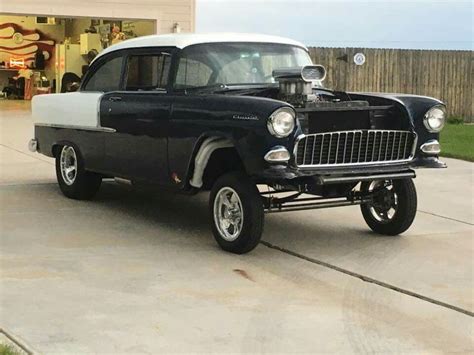 an old black and white car parked in front of a building