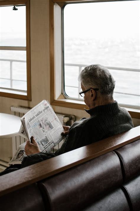 Man Sitting on Bench While Reading Newspaper · Free Stock Photo