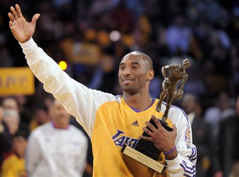 Bryant holds up the NBA’s Most Valuable Player trophy as he signals his teammates to come over ...