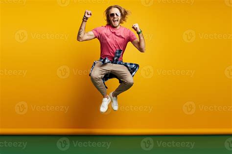 Excited young man gesturing while jumping against yellow background ...