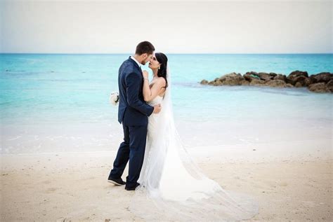 a bride and groom standing on the beach