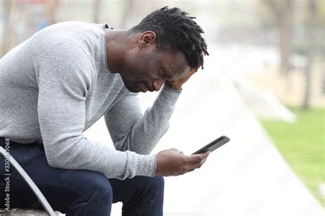 Sad black man complaining checking mobile phone Stock Photo | Adobe Stock