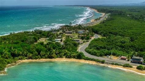 Waves rolling in toward a tree-lined beach in Loiza, Puerto Rico Aerial ...