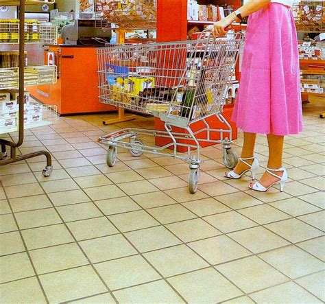 a woman in a pink dress is pushing a shopping cart through a grocery store aisle
