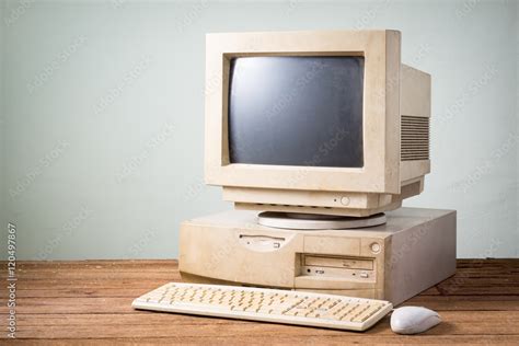 old and obsolete computer on old wood table with concrete wall background Stock Photo | Adobe Stock