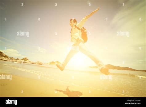 Happy young man jumping on beach Stock Photo - Alamy