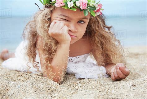 Portrait of a cute young girl laying on beach making a face;Waikiki oahu hawaii united states of ...