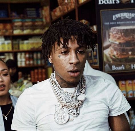 a man with dreadlocks standing in front of a store filled with food items