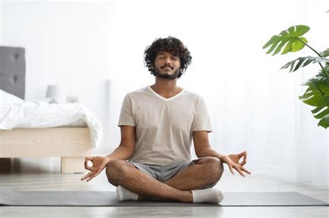 Premium Photo | Peaceful indian man practicing yoga at home meditating