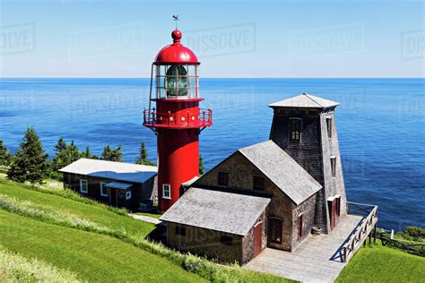 Pointe-a-la-Renommee lighthouse and houses against sea at sunny day ...