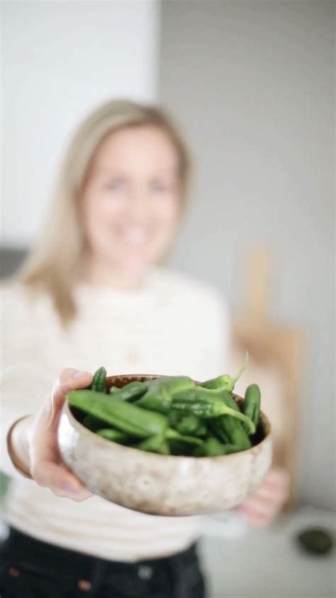a woman holding a bowl filled with green beans