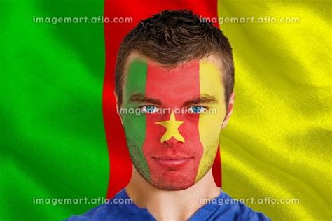 Composite image of serious young cameroon fan with facepaint against digitally generated ...