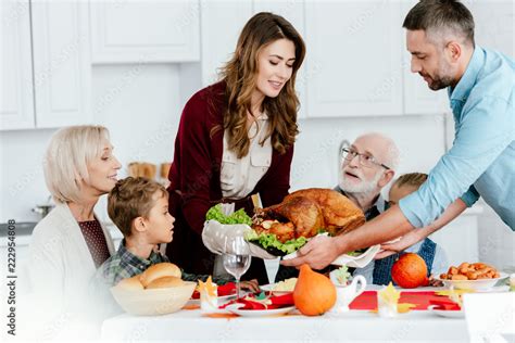 happy adult couple carrying baked turkey for thanksgiving dinner with ...