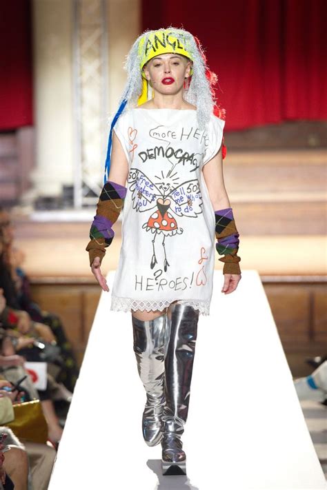 a model walks down the runway in a white dress with graffiti written on it and headbands