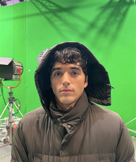 a man wearing a jacket and hat in front of a green screen with camera ...