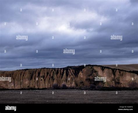 dusk looking over grey fields toward sluiced cliff a big rolling sky beyond kyeburn diggings ...