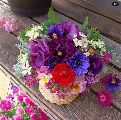 a basket filled with purple and red flowers sitting on top of a wooden picnic table