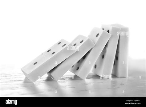Line of dominoes falling on light wooden background Stock Photo - Alamy