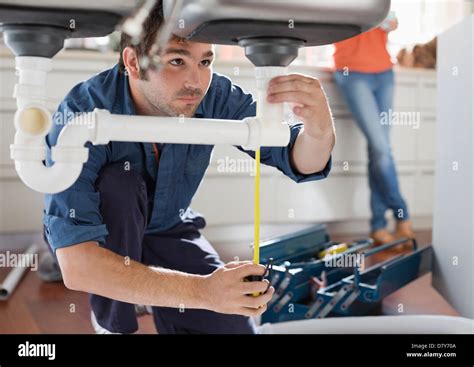 Plumber working on pipes under kitchen sink Stock Photo - Alamy