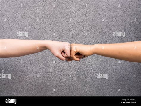 Arms of two young women fist bumping against gray background Stock ...