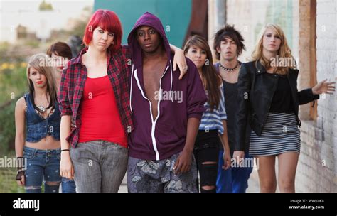 A pair of young punk teens pose together as their friends stay in the ...