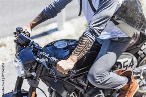 Tattoos on arms of motorcycle rider on custom made scrambler style cafe ...