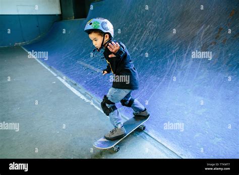 Skater kid skateboarding down a blue ramp Stock Photo - Alamy