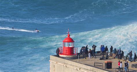 Nazare, Portugal - November 7, 2022 People watching a surfer riding a ...