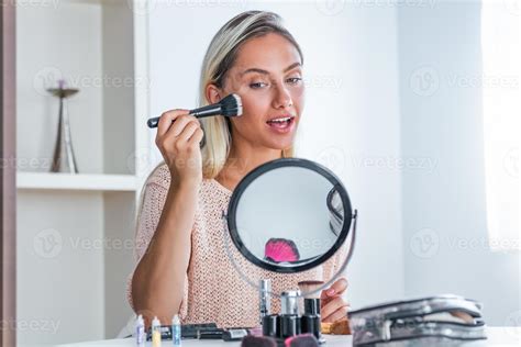 Beauty woman applying makeup. Beautiful girl looking in the mirror and ...