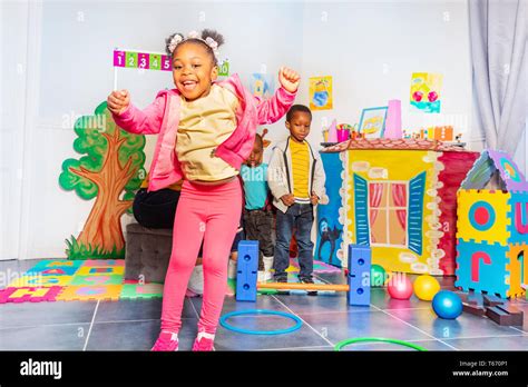 Girl jumps on circles in group of kids in kindergarten and teacher ...