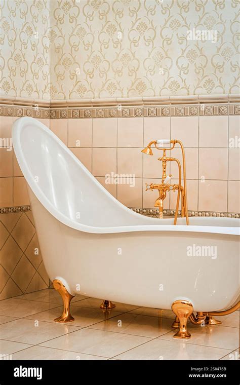 A vintage style bathtub with ornate golden clawfoot legs and matching ...