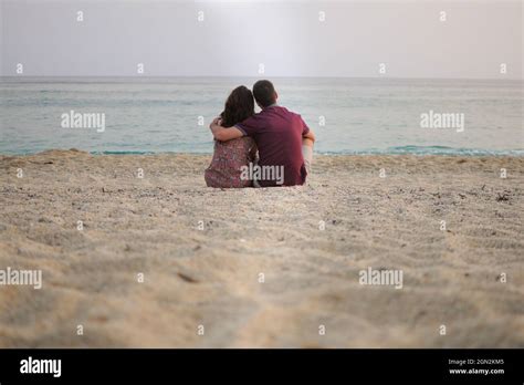 Un jeune couple homme et femme sont assis à la plage et regardent la ...