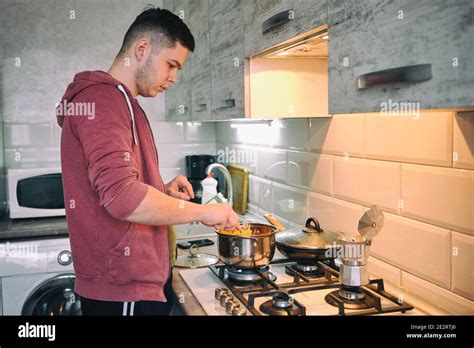 Man cooking pasta spaghetti at home in the kitchen. Handsome man ...
