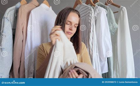 Uncertain Attractive Young Adult Posing Near Outfit Rail Holding Stack ...