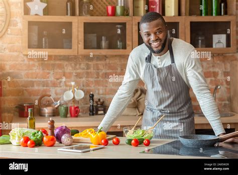 Attractive black man posing at kitchen while cooking Stock Photo - Alamy