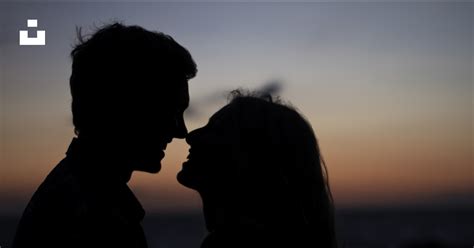 Silhouette d’homme et de femme sur le point de s’embrasser sur la plage ...