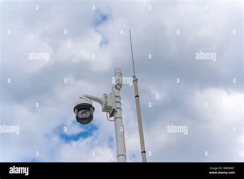 A modern surveillance camera is attached to a mast and directed towards ...