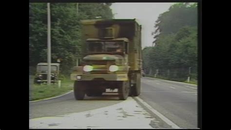1980s: Military trucks drive down highway. – Archival Footage