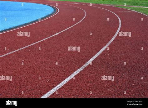 red running track curve with white lines, blue sports field in left ...