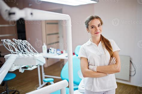 Good-looking female dentist posing in white coat in a modern well ...