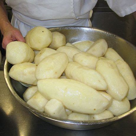 A Person In A White Shirt Is Cooking Some Food On A Silver Pan And