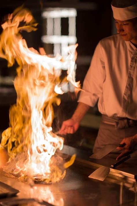 A Chef Is Cooking On A Grill With Flames Coming From It S Back End