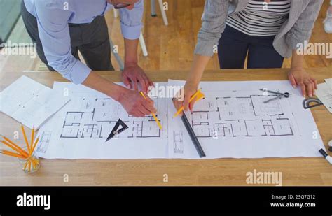 Close Up Male And Female Architects Working In Office Looking At Plans