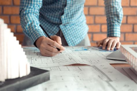 La Mano De Un Joven Ingeniero Dibujando En El Plano Con El Modelo En El