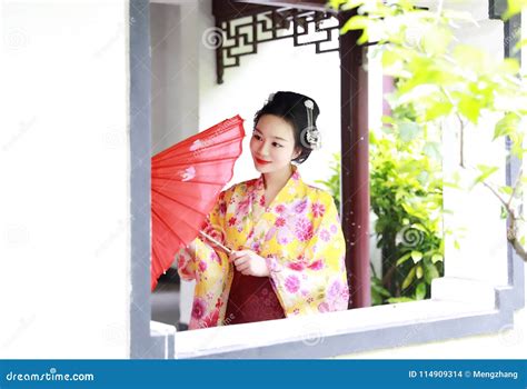 Traditional Asian Japanese Beautiful Geisha Woman Bride Wears Kimono Hold A Red Umbrella In A