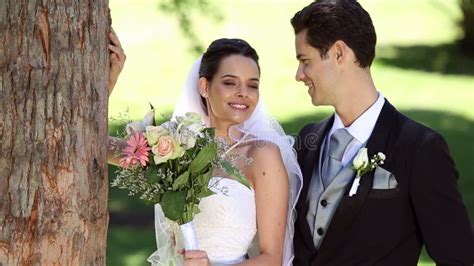 Recienes Casados Felices Que Se Colocan En El Parque Al Lado De Un