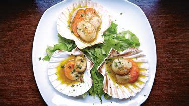 Scallops On A White Plate With Lettuce And Tomato Garnish