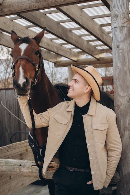 Premium Photo | Handsome young cowboy on a ranch with a horse