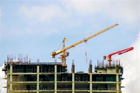 Hoisting crane and Construction crane working building construction on bright blue sky. 20164117 ...