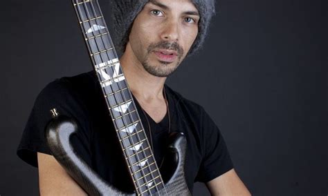 a man wearing a beanie and holding an electric guitar in front of his face